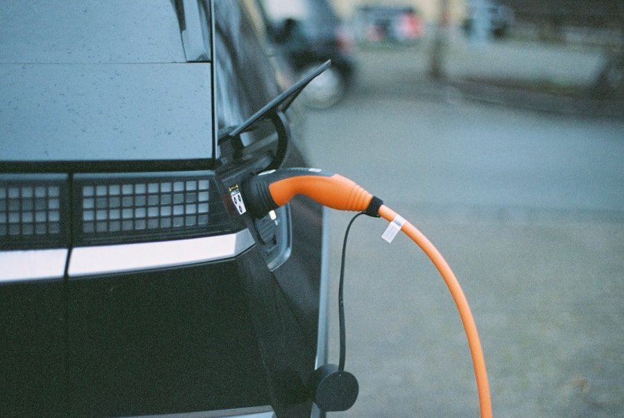 An electric vehicle is connected to a charging station with an orange cable.