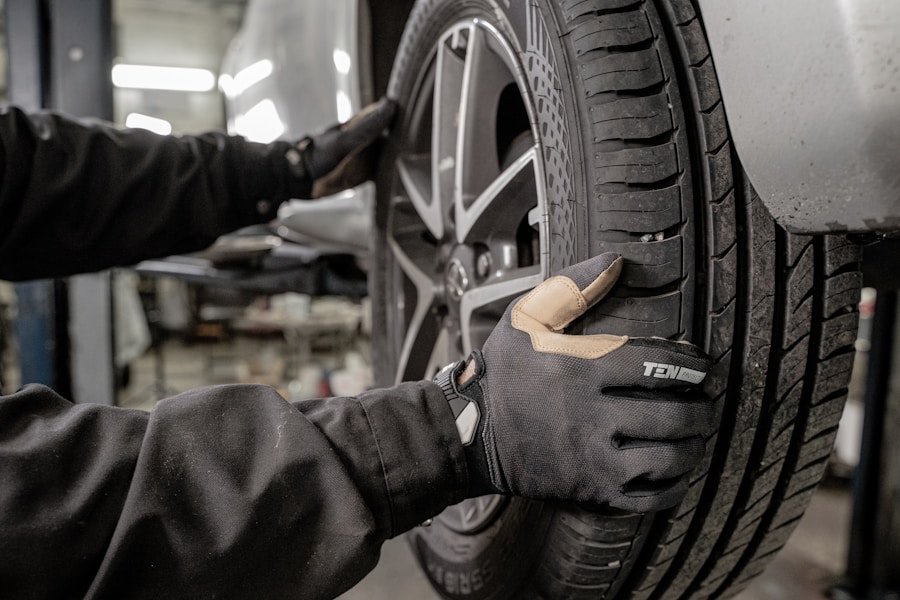 Mechanic wearing gloves adjusts a car tire in an auto repair shop.