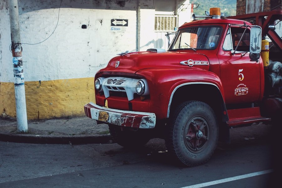 A vintage red tow truck parked on a street near a yellow and white wall.