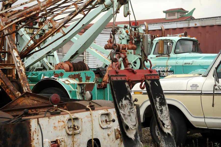 Rusty tow trucks parked in a lot with visible chains and hooks.